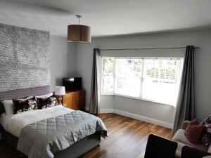 a bedroom with a bed and a large window at Foxhollow House Suite in Blarney