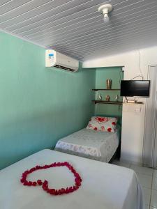 a room with two beds with a red necklace on them at Pousada Vale Encantado in São Miguel dos Milagres