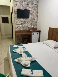 Una habitación de hotel con una cama con toallas. en Pousada Pedra Encantada, en São Thomé das Letras