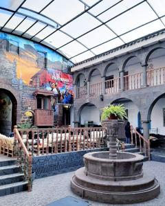 a building with a fountain in the middle of it at Pariwana Hostel Cusco in Cusco
