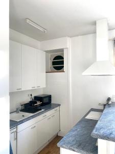 a white kitchen with a sink and a microwave at Quimper: T3 avec vue cathédrale proche gare in Quimper