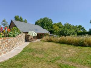 a house with a garden and a stone wall at The Old Parlour in Sampford Courtenay