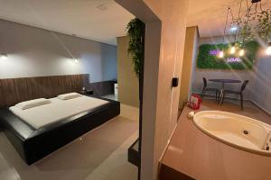 a bedroom with a bed and a tub and a sink at Lotu's Motel in Arapiraca