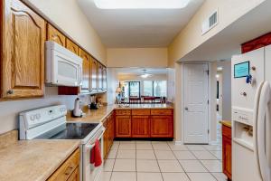 a kitchen with wooden cabinets and white appliances at Palm Beach Club #126 in Pensacola Beach