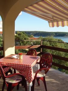 a table and chairs on a patio with a view of the water at Apartments and rooms by the sea Supetarska Draga - Gonar, Rab - 2002 in Supetarska Draga