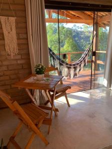 a table and chairs in a room with a balcony at Chalés Água azul in Santo Antônio do Pinhal