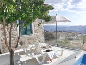 a patio with two chairs and a table and an umbrella at Casinha da Colina in Alfândega da Fé