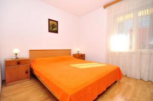 1 dormitorio con cama de color naranja y ventana en Apartments by the sea Arbanija, Ciovo - 1085 en Trogir