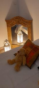 um urso de peluche sentado numa cama em frente a um espelho em B&B Chez Odile em Mirabel