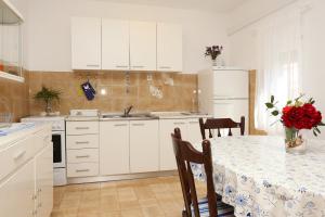 una cocina con una mesa con un jarrón de rosas rojas en Apartments by the sea Okrug Gornji, Ciovo - 1111 en Trogir