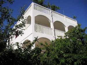 un edificio blanco con árboles delante de él en Apartments by the sea Mavarstica, Ciovo - 1120 en Trogir