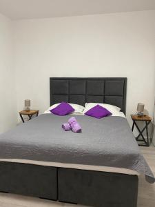 Una cama con almohadas púrpuras y zapatos púrpura. en Apartment Arbanija 1122a en Trogir