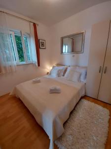 1 dormitorio con 1 cama blanca grande y espejo en Apartments by the sea Mavarstica, Ciovo - 1120 en Trogir