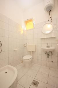 Baño blanco con aseo y lavamanos en Apartment Arbanija 1122a en Trogir