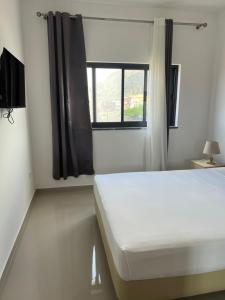 a bedroom with a white bed and a window at Tarrafal Apartments in Tarrafal