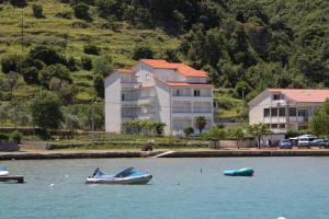 a boat in the water in front of a house at Apartments and rooms by the sea Supetarska Draga - Donja, Rab - 2001 in Rab