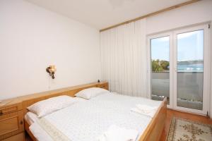 a bedroom with a bed and a large window at Apartments and rooms by the sea Supetarska Draga - Donja, Rab - 2001 in Rab