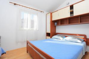 a bedroom with a bed with blue sheets and a window at Apartments with a parking space Slatine, Ciovo - 2030 in Trogir