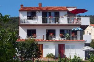 a white house with a balcony with flowers on it at Apartments by the sea Slatine, Ciovo - 2039 in Slatine