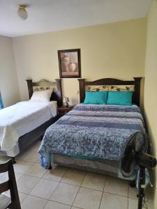 a bedroom with two beds with blue pillows at El Ático Guatemala in Guatemala