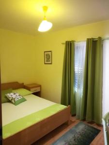 Schlafzimmer mit einem Bett und einem Fenster mit grünen Vorhängen in der Unterkunft Seaside house for families with children Cove Tvrdni Dolac, Hvar - 2057 in Gdinj