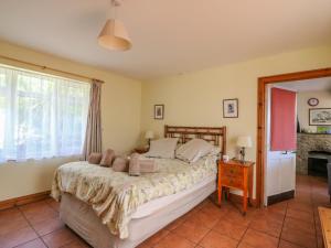 1 dormitorio con cama y ventana en Mimosa Cottage, en Swyre