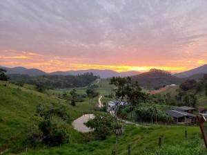 a sunset on a hill with a pond in a field at CABANA PARAÍSO in Santo Amaro da Imperatriz