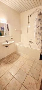 a white bathroom with a tub and a sink at Ruim nostalgisch gelijkvloers appartement op wandelafstand van de zee in Blankenberge