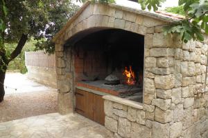 a stone pizza oven with a fire in it at Apartments by the sea Cove Ljubljeva, Trogir - 2194 in Voluja