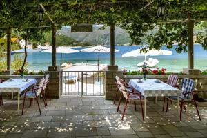 a patio with tables and chairs and a view of the ocean at Apartments and rooms by the sea Zaton Veliki, Dubrovnik - 2110 in Zaton