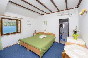 a bedroom with a green bed and a window at Apartments and rooms by the sea Zaton Veliki, Dubrovnik - 2110 in Zaton