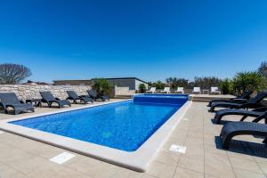 a swimming pool with chaise lounges and chairs at Family friendly apartments with a swimming pool Valbandon, Fazana - 2201 in Štinjan