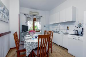 a kitchen with a table and chairs and a kitchen with white cabinets at Family friendly apartments with a swimming pool Valbandon, Fazana - 2201 in Štinjan