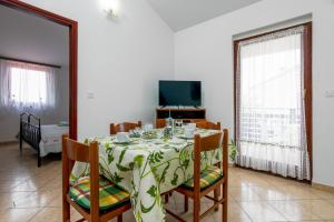 a dining room with a table and chairs and a television at Family friendly apartments with a swimming pool Valbandon, Fazana - 2201 in Štinjan