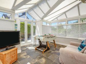 Una sala de estar con un televisor y una mesa. en Bryn Rhosyn, en Pwllheli