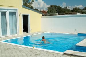een persoon in een zwembad naast een huis bij Double Room Peroj 2235d in Peroj