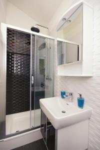 a white bathroom with a sink and a shower at Apartments by the sea Mudri Dolac, Hvar - 4026 in Vrboska