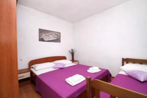 duas camas num quarto com lençóis roxos e toalhas em Secluded fisherman's cottage Cove Skozanje, Hvar - 4039 em Gdinj