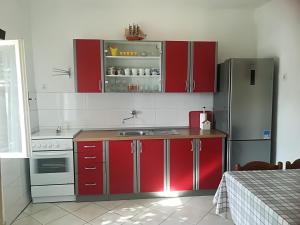uma cozinha com armários vermelhos e um frigorífico de aço inoxidável em Secluded fisherman's cottage Cove Skozanje, Hvar - 4039 em Gdinj
