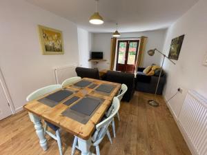 - un salon avec une table et des chaises en bois dans l'établissement Stable Cottage, à Winscombe