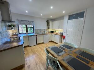 a kitchen with a wooden table and a dining room at Stable Cottage in Winscombe