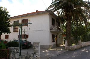 a white house with a palm tree in front of it at Double Room Jelsa 4041d in Jelsa