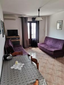 uma sala de estar com uma mesa e um sofá roxo em Apartments with a parking space Metajna, Pag - 4127 em Zubovici