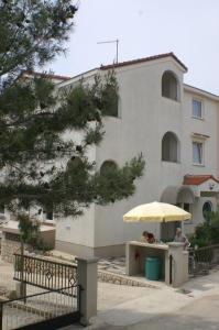 two people sitting at a table under an umbrella in front of a building at Apartment Mandre 4098d in Mandre +18 photos