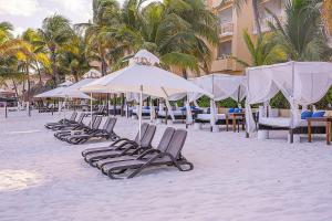 een rij ligstoelen en parasols op een strand bij All Ritmo Cancun Resort & Water Park in Cancun