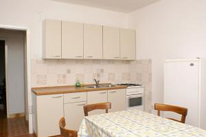 kuchnia z białymi szafkami, stołem i zlewem w obiekcie Family friendly seaside apartments Vlasici, Pag - 4131 w mieście Vlašići