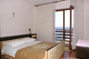 a bedroom with a bed with a view of the ocean at Rooms by the sea Cove Mulobedanj, Pag - 4061 in Lun