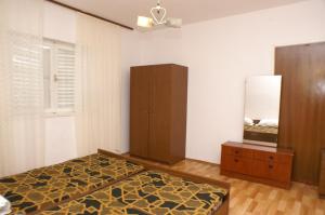 Schlafzimmer mit einem Bett, einer Kommode und einem Spiegel in der Unterkunft Apartment Grebastica 4207b in Bašelovići