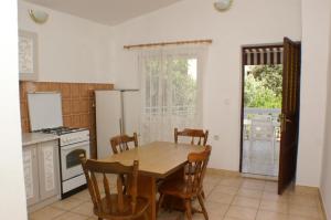 eine Küche mit einem Tisch und Stühlen sowie einem Kühlschrank in der Unterkunft Apartment Grebastica 4207b in Bašelovići