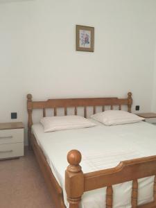une chambre avec un lit en bois avec des draps blancs dans l'établissement Apartment Potocnica 4096d, à Stara Novalja